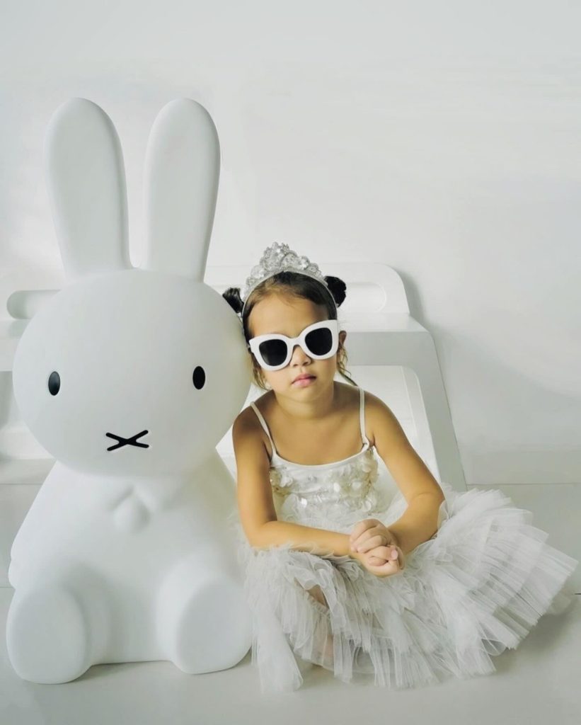 Girl sitting beside a giant Miffy lamp, showcasing the lamp's silhouette.