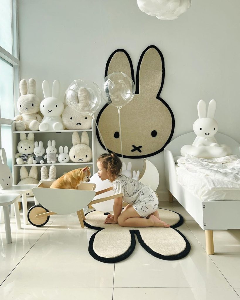 Young girl and dog sitting in a Miffy-themed room, with a Miffy wall rug in the background.