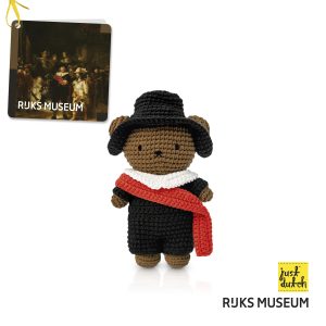 Knitted brown bear in a black outfit and hat with a red scarf.